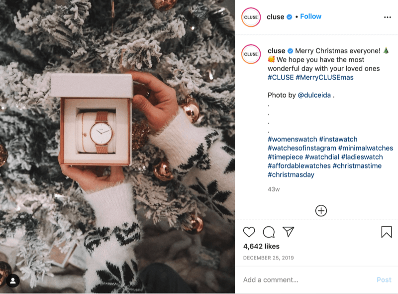 post di instagram di @cluse che mostra la foto di una modella con il maglione con il fiocco di neve che tiene un orologio davanti a un albero innevato di @dulceida con gli hashtag #cluse e #meryclusemas