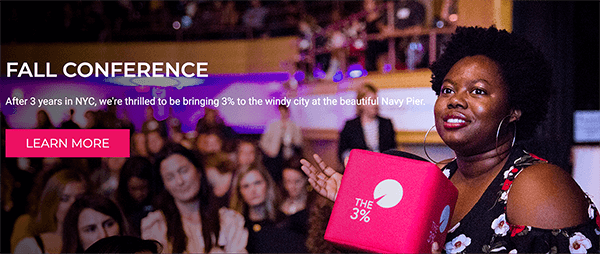 Questo è uno screenshot dal sito web per The 3% Conference. In una foto, una donna nera tiene in mano un cubo rosa brillante con il logo della conferenza stampato su di esso. Dietro di lei c